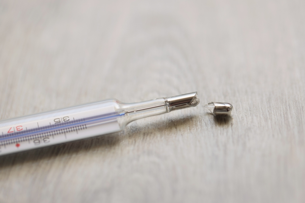 Close-up of broken glass mercury thermometer lying on floor