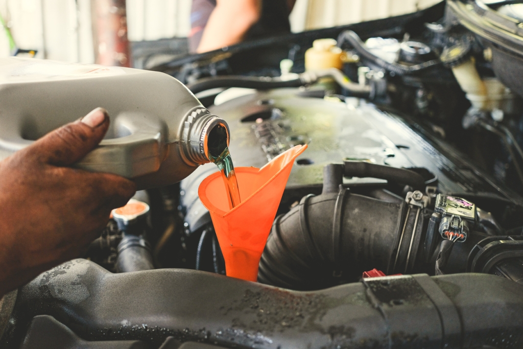 Car technician pouring transmission fluid at the car service station.