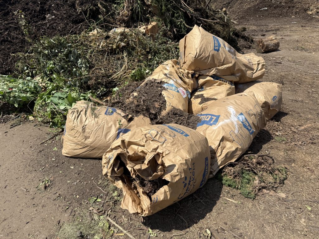 bags of yard water next to a large pile of brush