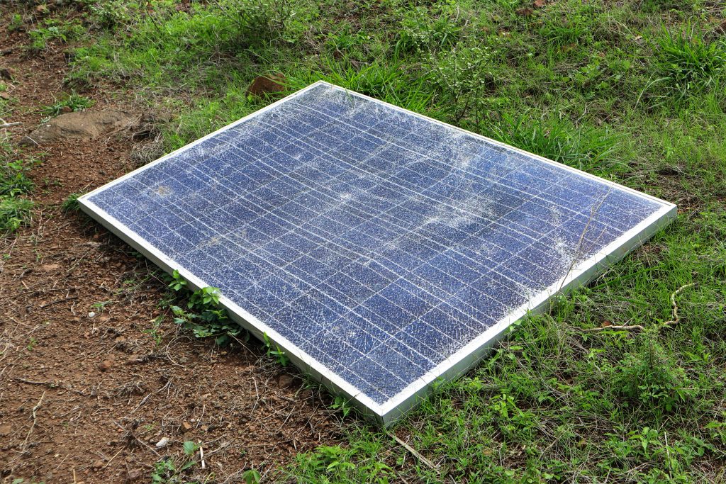 A damaged solar panel is shown on the ground.
