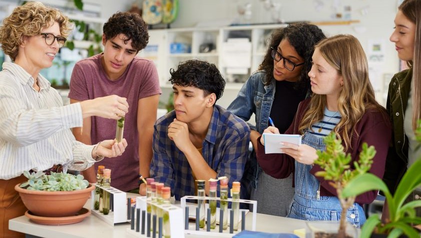 Mature science teacher showing sample in test tube to a group of multiethnic students